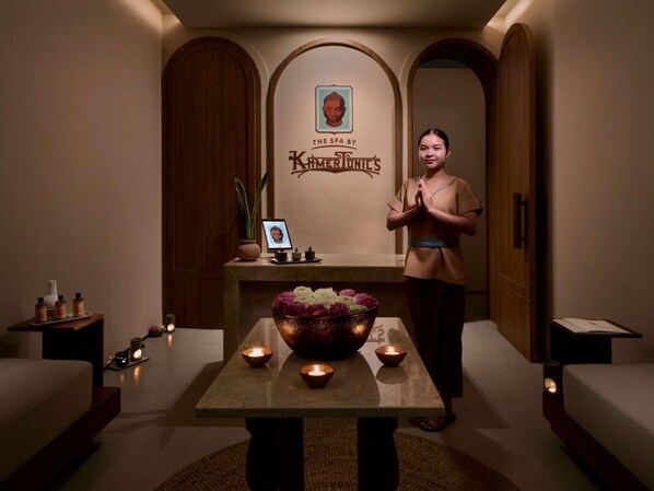 Ein Wellnessbereich mit Rezeption, einer Wandtafel, einem Tisch mit Kerzen und einer dekorativen Blumenarrangements.