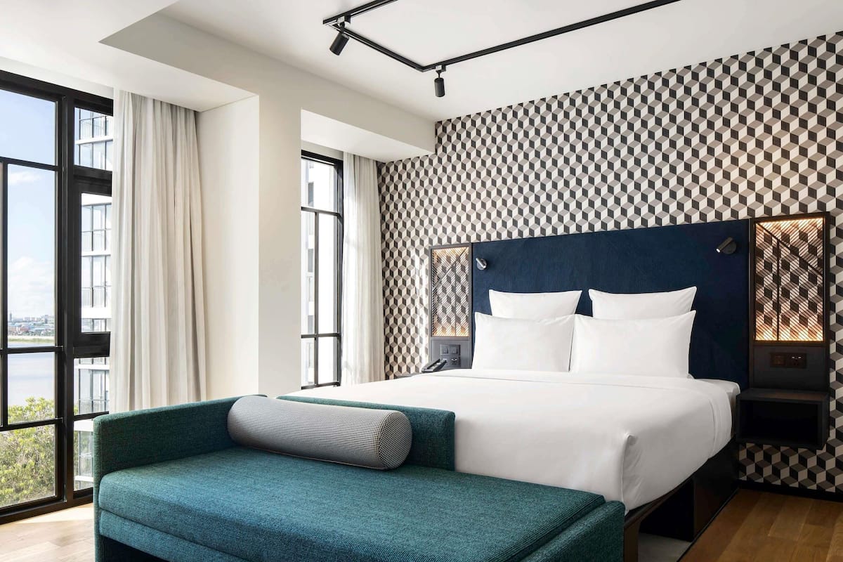 Une chambre dâhĂŽtel moderne avec un grand lit, un canapĂ©, une vue par la fenĂȘtre et un mur dĂ©corĂ© de motifs.