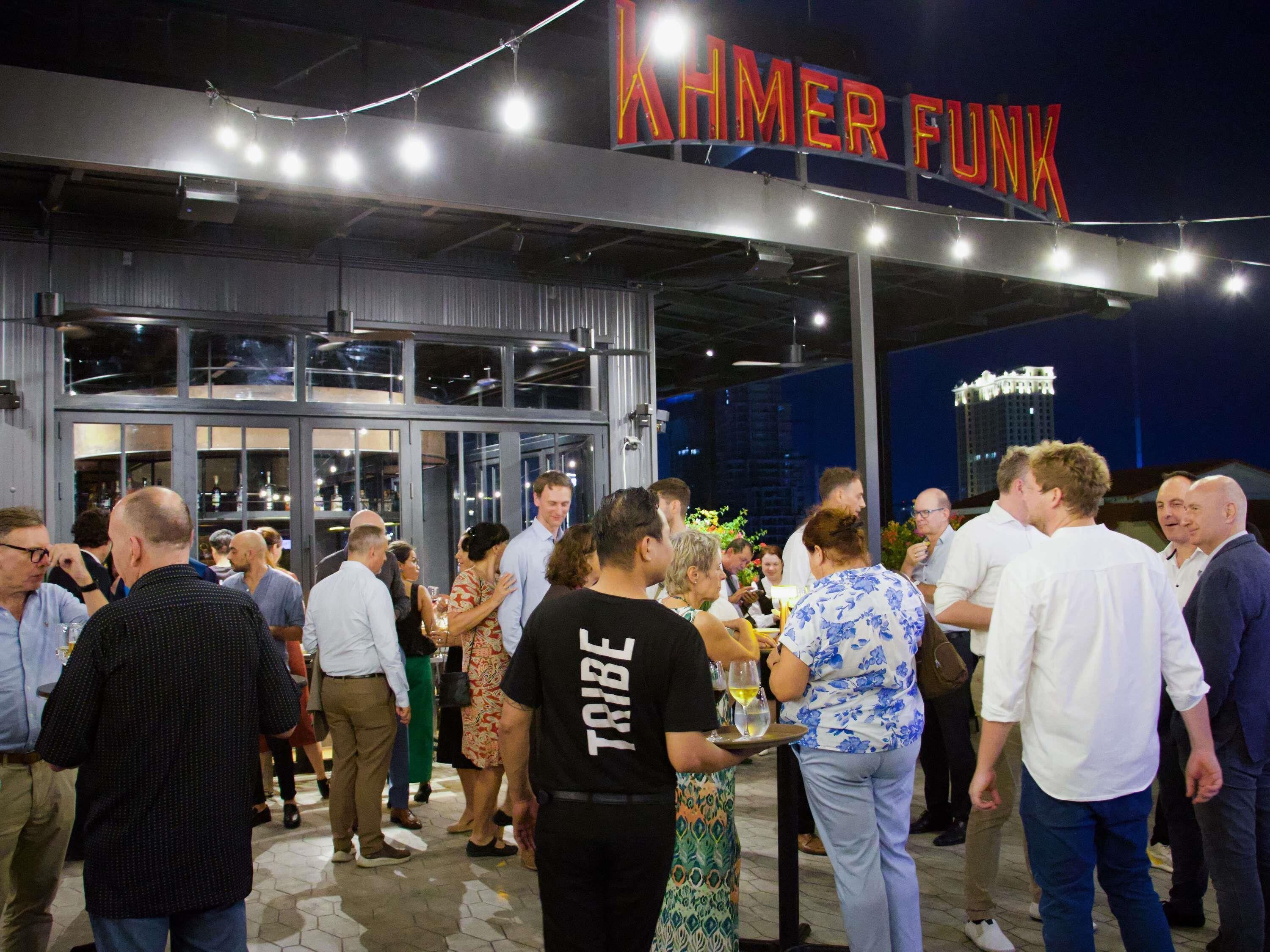 Un grupo de personas reunidas frente a un edificio con un letrero que dice 'XAHMER FUNK'.