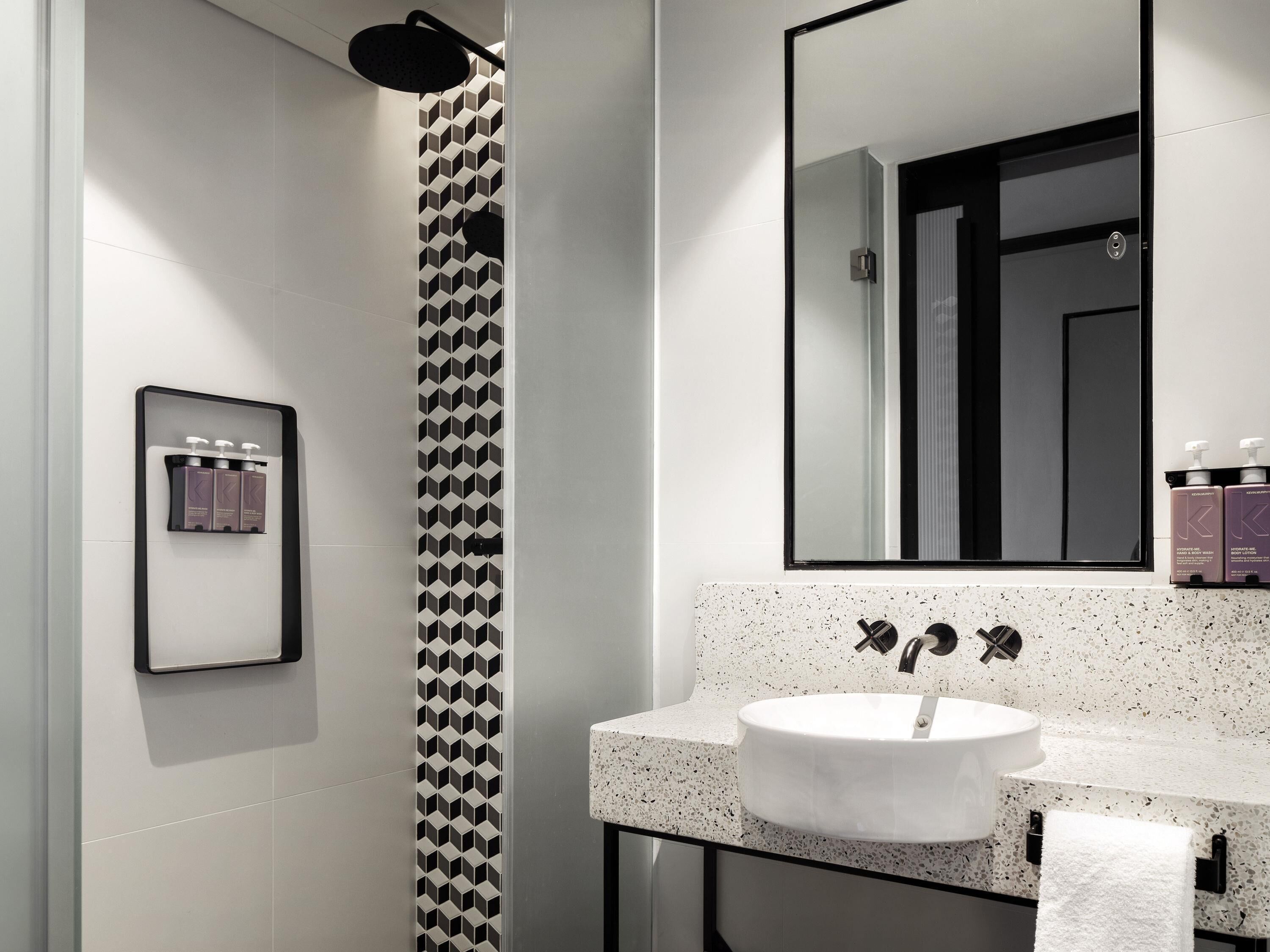 Une salle de bain moderne avec une douche, un lavabo et un miroir.
