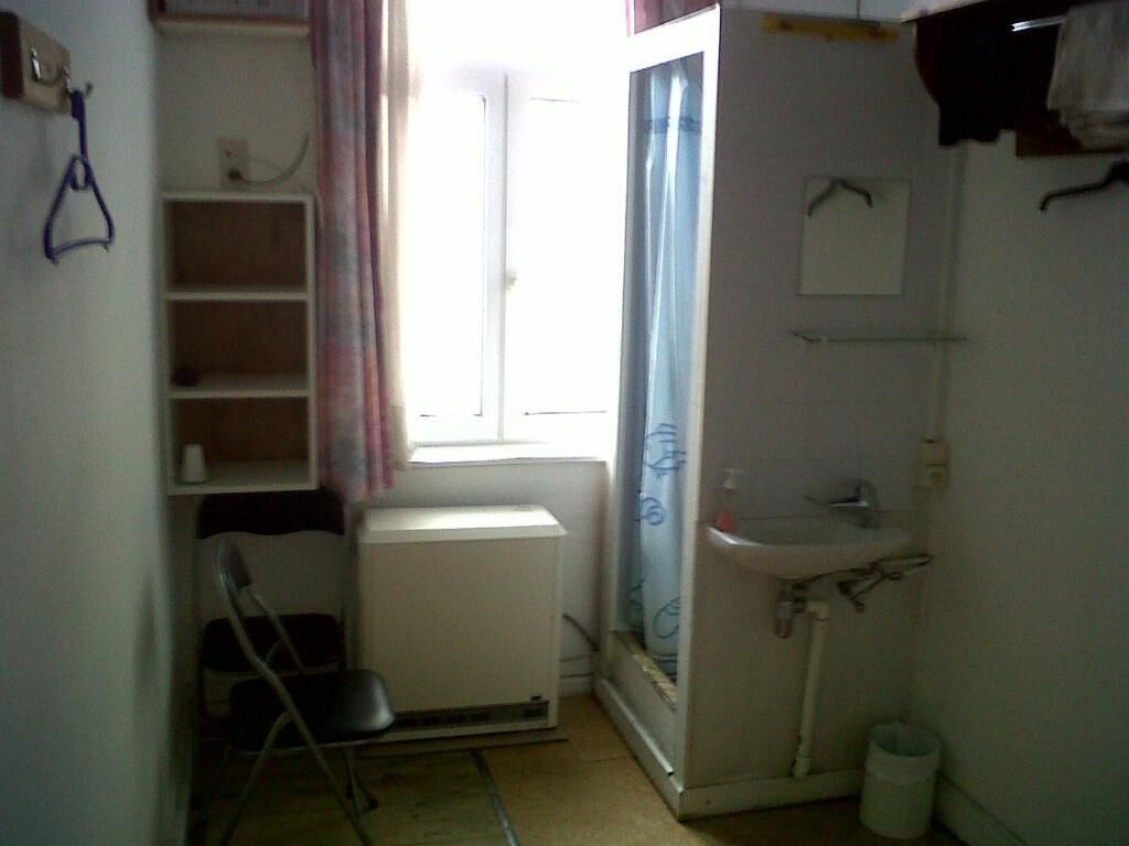 Ein kleines, kompaktes Badezimmer mit Heizkörper, Waschbecken und Duschbereich.