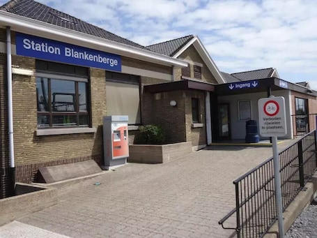 A train station named 'Station Blankenberge' with a ticket machine and a sign indicating 'Ingang' for entry.