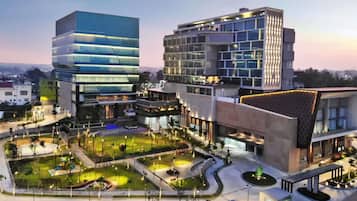 A modern building complex with multiple floors, a landscaped courtyard, and a parking area.