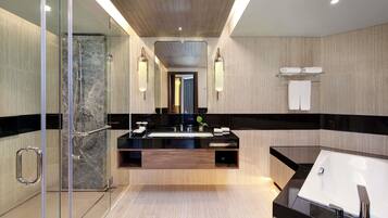 A modern bathroom with a glass shower enclosure, a central sink with a black countertop, and a separate bathtub.
