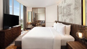 A modern hotel room with a large bed, a flat-screen TV, a desk, and a large window offering a city view. - Mercure Pangkalan BUN (Pangkalan Bun)