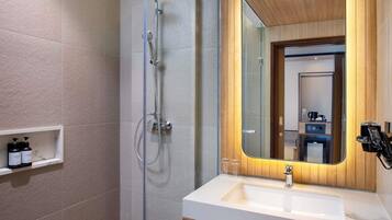 Un baño moderno con ducha, lavamanos y espejo.