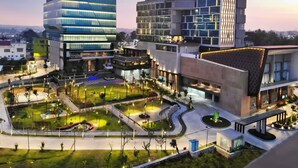 Un ensemble immobilier moderne comprenant plusieurs étages, une cour aménagée et un espace de stationnement.
