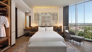 A modern hotel room with a large bed, a seating area, a wardrobe, and a city view. - Mercure Pangkalan BUN (Pangkalan Bun)