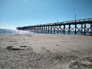 Una playa con un muelle que se adentra en el océano.