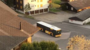 Ein Bus steht auf einem Parkplatz, im Hintergrund sind Gebäude zu sehen.
