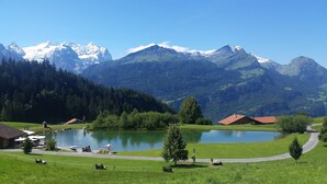 Eine friedliche Seenlandschaft mit Blick auf schneebedeckte Berge, einem kleinen Steg und einem Picknickplatz.