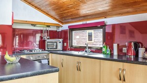 Une cuisine avec des meubles de rangement en bois, un four à micro-ondes, un évier et une fenêtre.