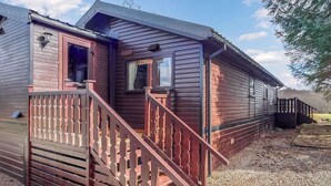 Une cabane en bois avec un escalier en bois menant à une porte, une fenêtre et un petit espace porche.