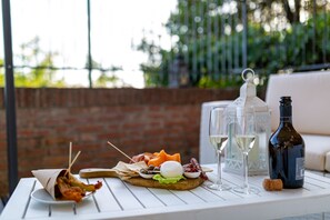 A table with a charcuterie board, two glasses of white wine, a bottle of wine, and a cork. - La Corte del Grillo - Residenza d'Epoca (Chiusi)
