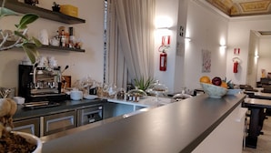 A modern kitchen with a coffee machine, breakfast bar, and various food items. - La Corte del Grillo - Residenza d'Epoca (Chiusi)