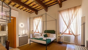 A four-poster bed with a green bedspread, a bedside table with a lamp, and a radiator. - La Corte del Grillo - Residenza d'Epoca (Chiusi)