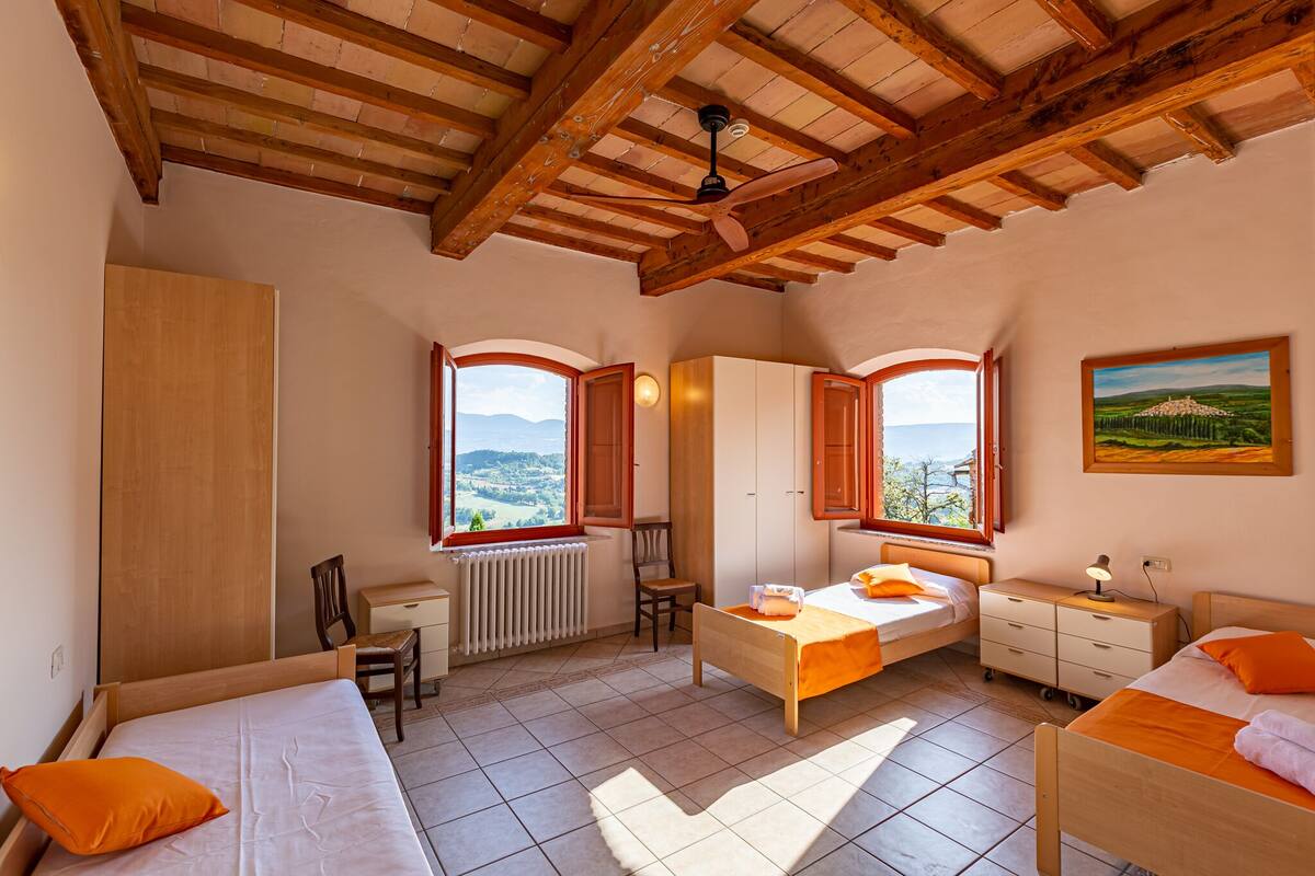 Un dormitorio con vigas de madera, un escritorio, dos camas, una silla y vistas al paisaje.