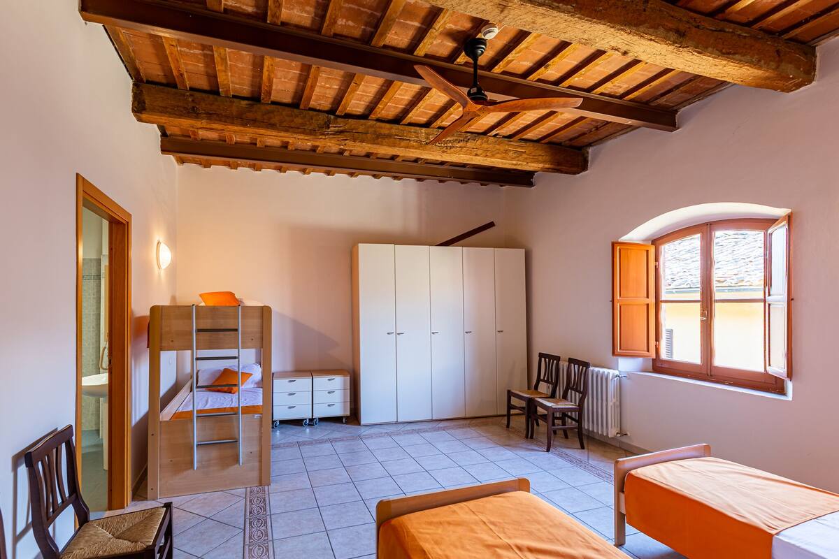 Un dormitorio con una cama litera, un armario, un escritorio y una silla.