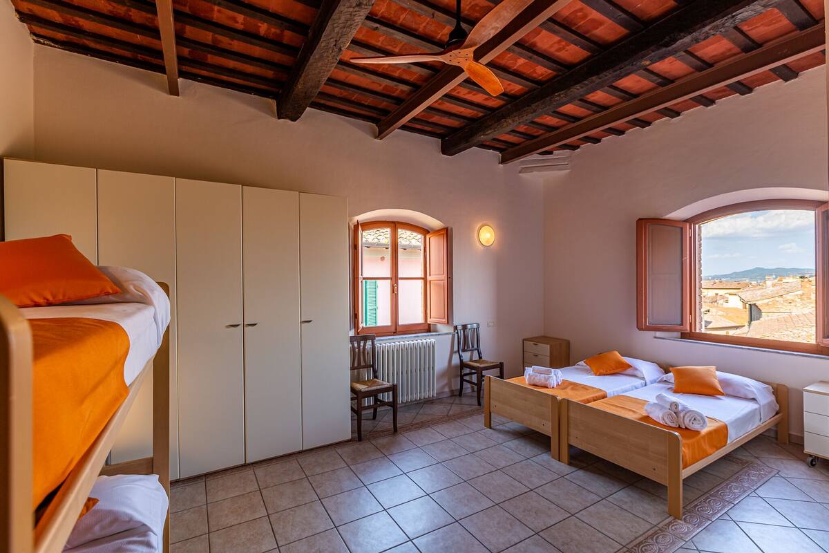 Una habitación con literas, dos camas individuales, un escritorio, sillas y una ventana con vistas.
