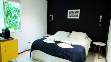 Quarto com uma cama, um armário amarelo, uma janela e um quadro pendurado na parede.