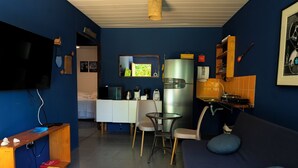 Un espacio habitable compacto con kitchenette, comedor y zona de estar.