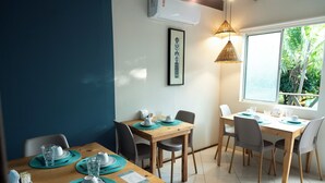Un comedor con mesas de madera, individuales color turquesa y platos blancos.