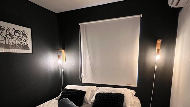 Una habitación de hotel moderna con una cama grande, una mesita redonda y una ventana con cortinas.