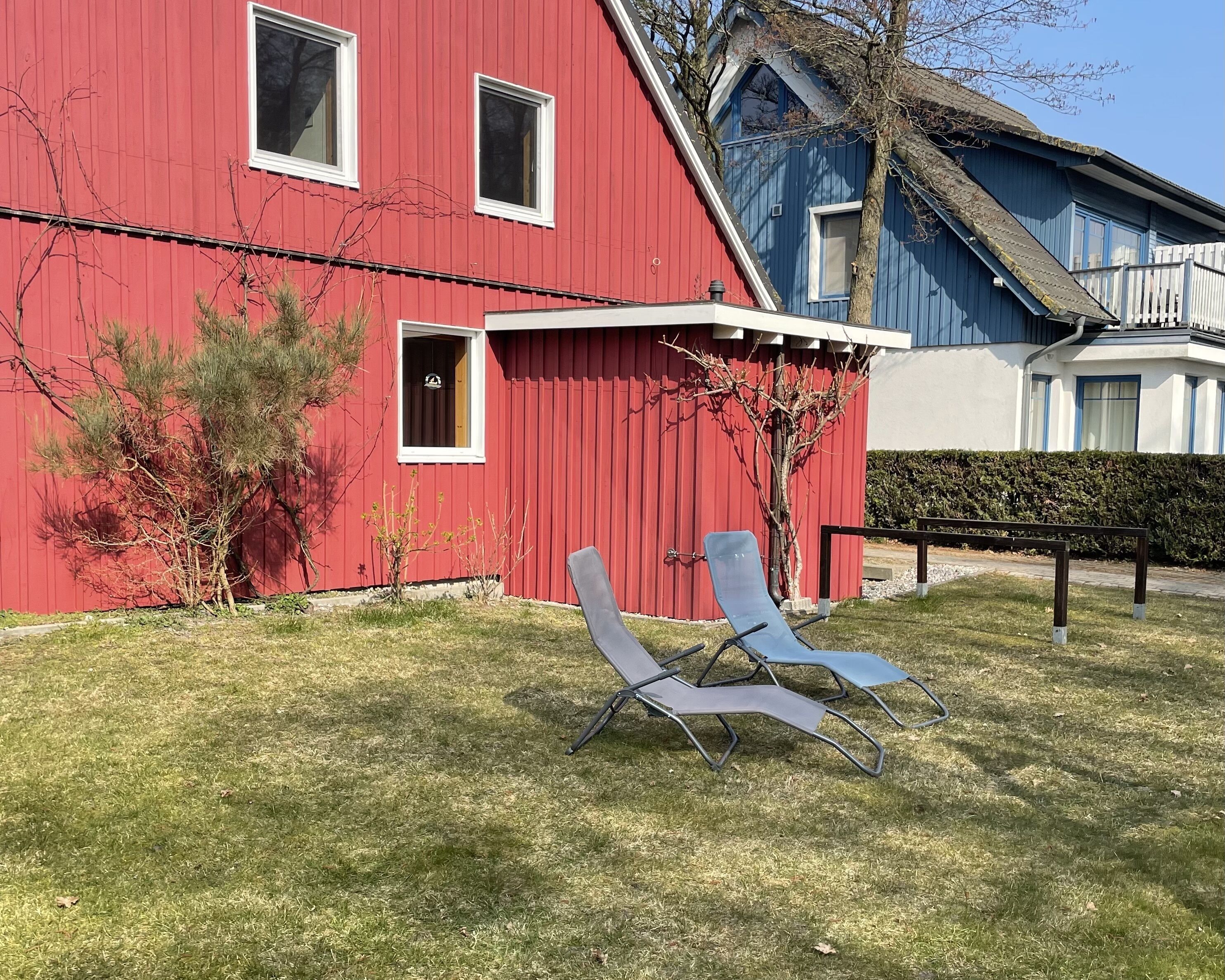 A red building with a small porch and two lounge chairs in front.