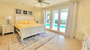 A bedroom with a bed, nightstands, a ceiling fan, and a view of a pool. - Front Row Beach House 6BR/5.5 bath private pool and private beach access. (Miramar Beach)