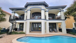 A two-story house with a swimming pool, balconies, and outdoor furniture. - Front Row Beach House 6BR/5.5 bath private pool and private beach access. (Miramar Beach)