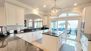 A spacious kitchen with white cabinetry, a granite countertop, and a large island. - Front Row Beach House 6BR/5.5 bath private pool and private beach access. (Miramar Beach)