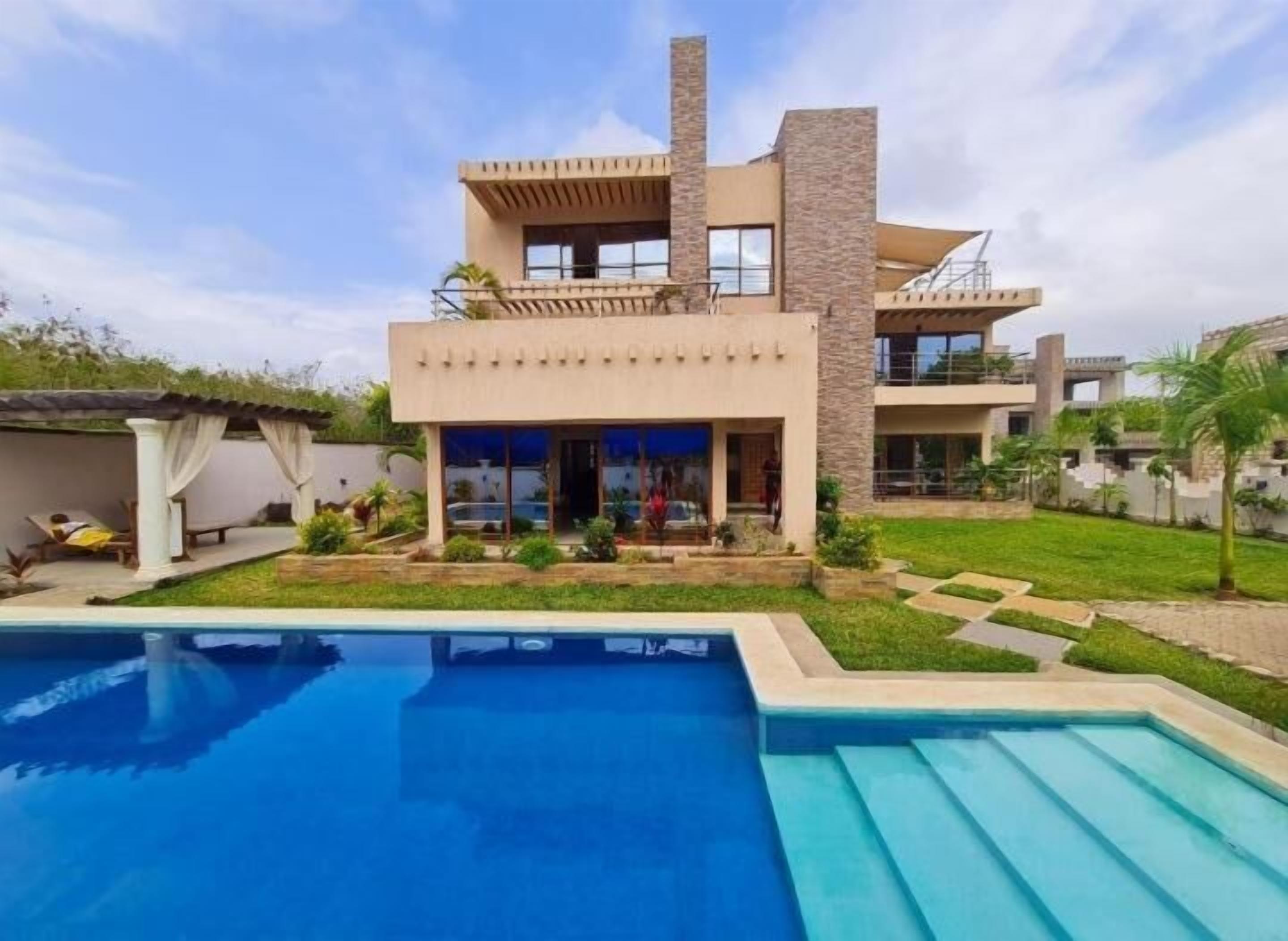 Uma casa moderna de dois andares com uma piscina em primeiro plano.
