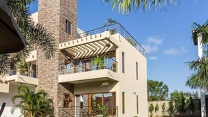 A modern two-story house with a stone tower, a balcony, and a well-maintained lawn. - Stay.Plus Diani Luxurious Villa (Diani Beach)