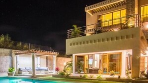 A modern two-story house with a swimming pool, outdoor seating, and a well-lit balcony. - Stay.Plus Diani Luxurious Villa (Diani Beach)