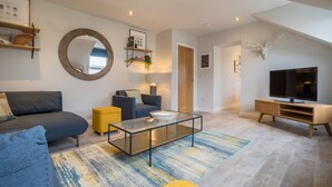 A modern living room with a sofa, coffee table, and TV stand. - Howe Keld 6 Second Floor (Keswick)