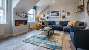 A modern living room with a fireplace, a sofa set, and a coffee table. - Howe Keld 6 Second Floor (Keswick)