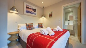 A hotel room with a bed, a bedside table, a mirror, and a door leading to a bathroom. - Howe Keld 6 Second Floor (Keswick)