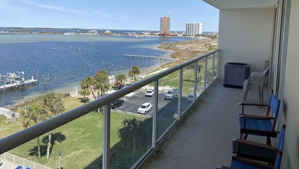 A balcony with a view of a marina, a parking lot, and a distant building. - Wake up with a view in a beautiful condo (Pensacola Beach)