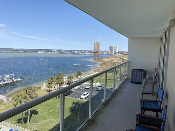 A balcony with a view of a marina, a parking lot, and a distant building.