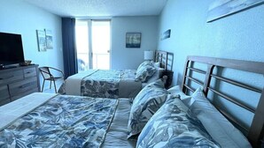 A hotel room with two beds, a TV, a desk, and a chair. - Wake up with a view in a beautiful condo (Pensacola Beach)