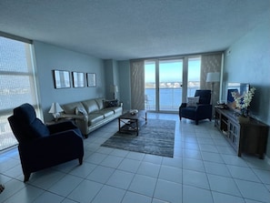 A spacious living room with a sofa, armchairs, a coffee table, and a TV stand.