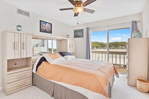 Relax in this serene bedroom with a large bed, wardrobe, and ceiling fan, offering a view of the outdoors.