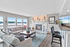 Relax by the fireplace in this inviting living room with a sofa, coffee table, and chair, offering a view of the outdoors.