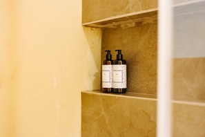 A bathroom shelf with two bottles of lavender-scented shampoo.