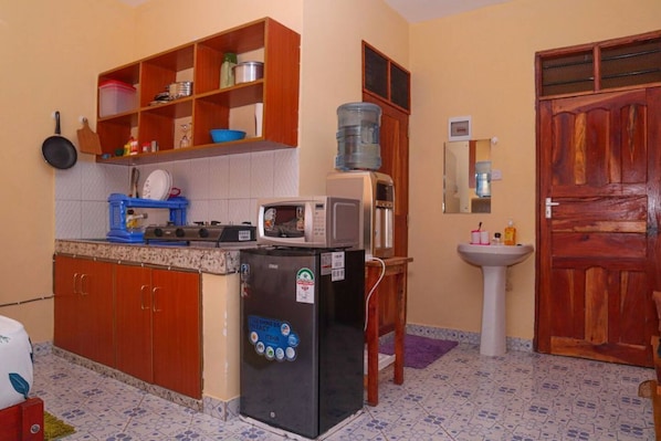 A compact kitchen with a refrigerator, microwave, and a water dispenser on the counter.