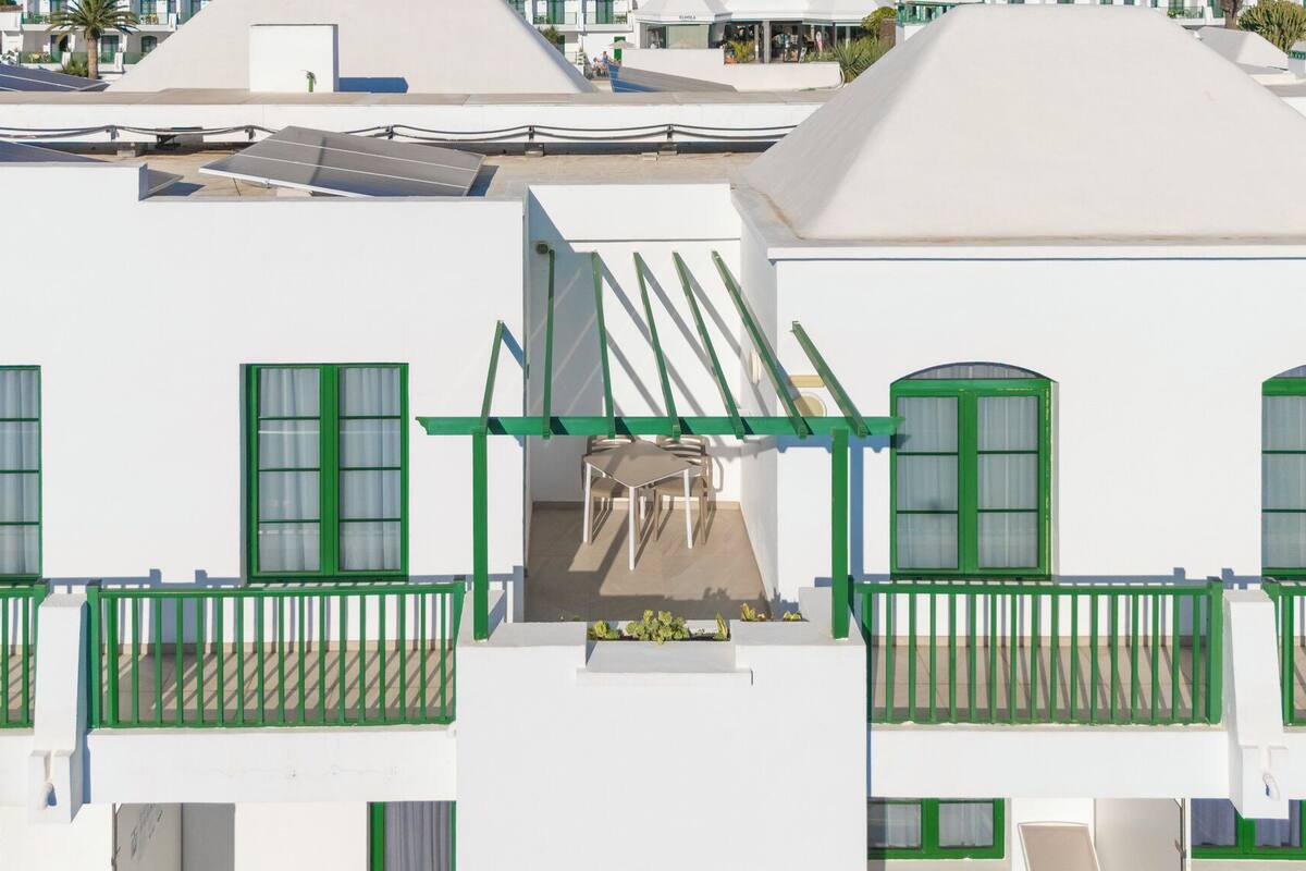 A white building with green-framed windows and balconies.