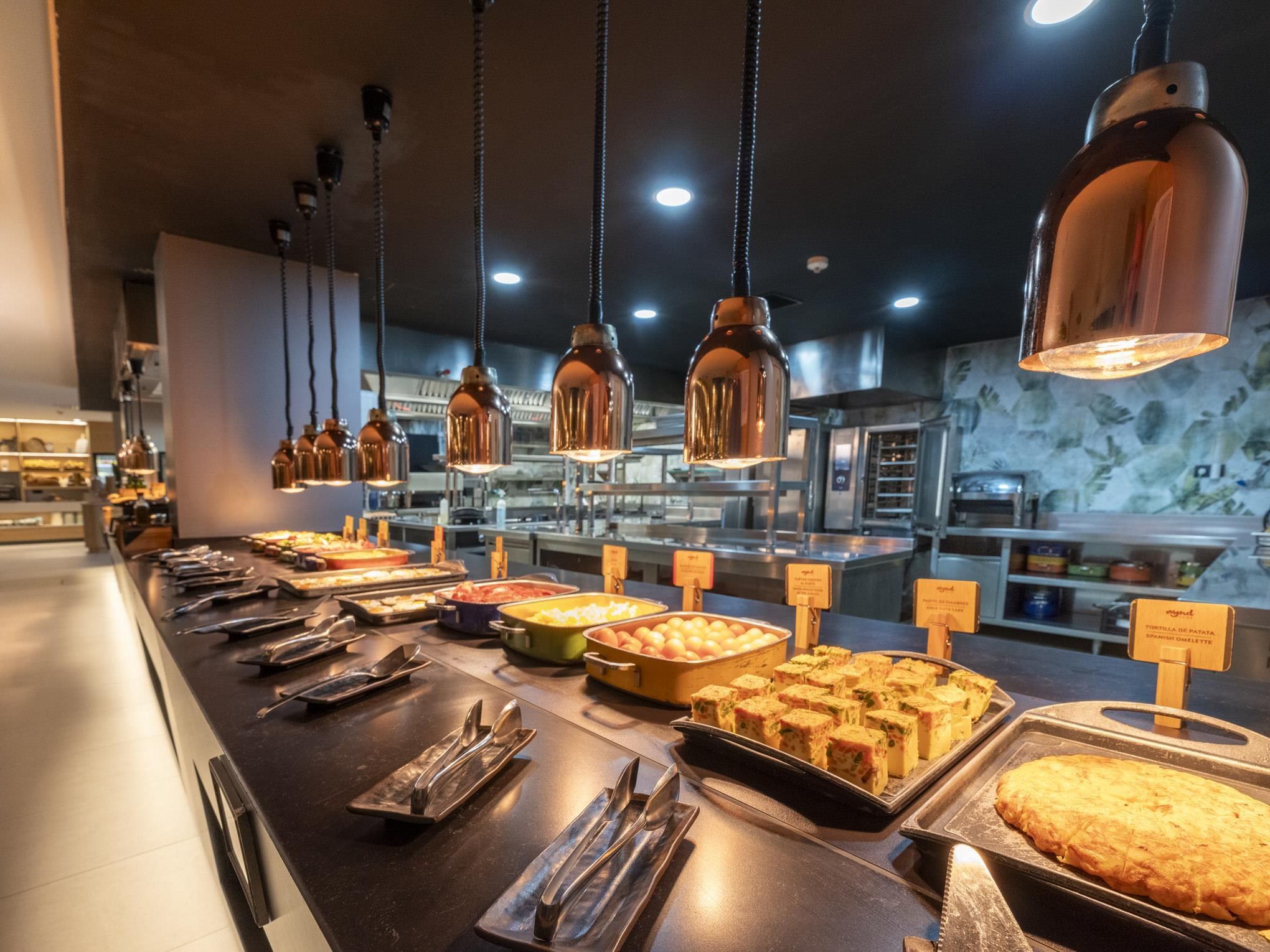Zona de bufé con distintos alimentos y utensilios.