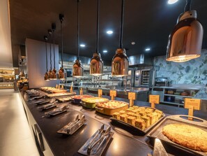 Zona de buffet amb diferents plats i utensilis.