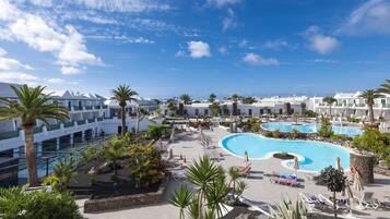 Ein Resort mit mehreren Swimmingpools, Palmen und blauem Himmel.