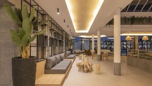 Een modern interieur met een lange bank, houten tafels en een grote kamerplant.